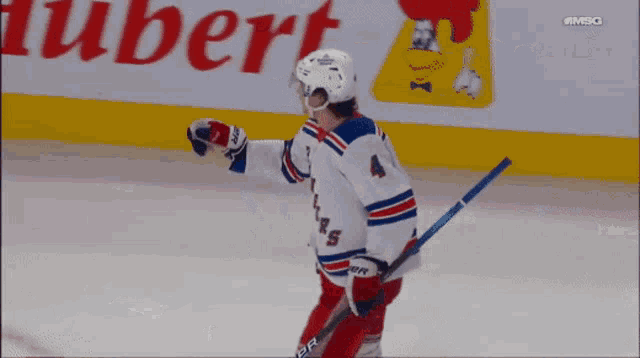 a hockey player stands on the ice in front of a hubert advertisement