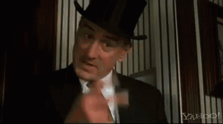 a man wearing a top hat and a suit is making a funny face