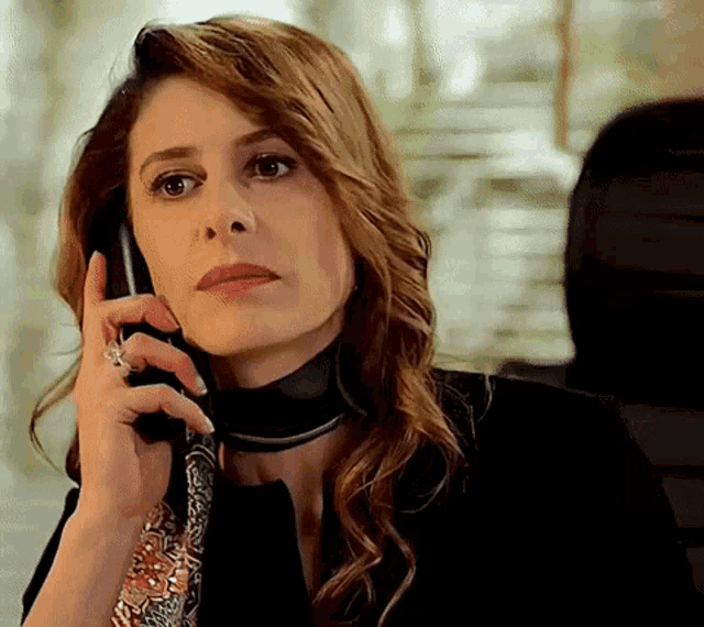 a woman is talking on a cell phone while wearing a black jacket