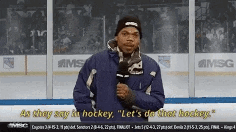 a man is holding a microphone in front of a hockey rink and says " as they say in hockey "