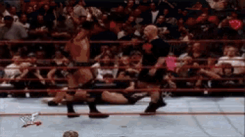 a man in a black shirt that says ' wwe ' on it stands in a wrestling ring