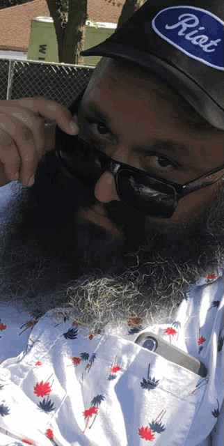 a man with a beard wearing sunglasses and a hat with the word riot on it