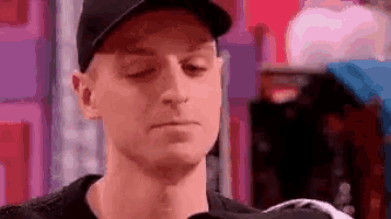 a man wearing a baseball cap and a black shirt is looking down at something .
