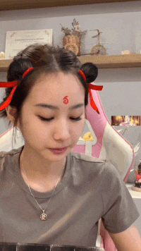 a woman with red ribbons in her hair has a red circle on her forehead