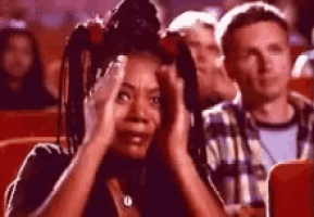 a woman is holding her head while sitting in a movie theater .