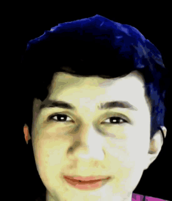 a young man with blue hair is smiling for the camera