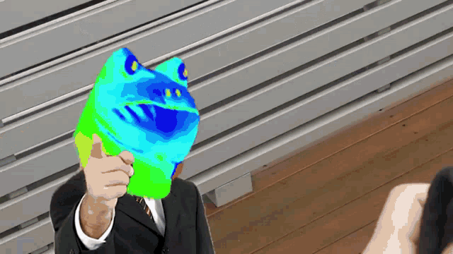 a man in a suit is holding a frog mask in front of his face