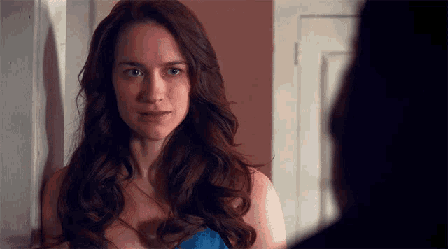 a woman with long red hair looks at a man