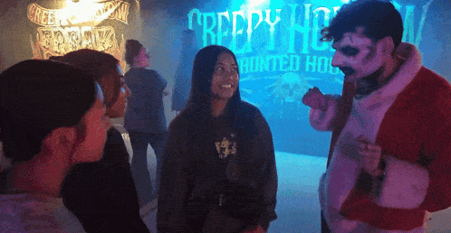 a group of people are standing in front of a creepy house sign
