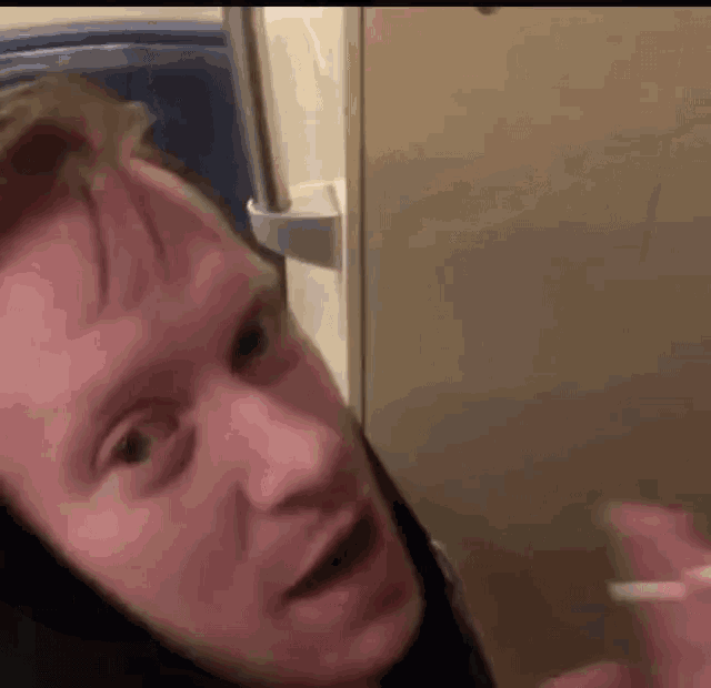 a man is standing in front of a refrigerator and looking at the camera .