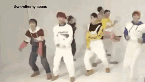 a group of people are standing next to each other and dancing .