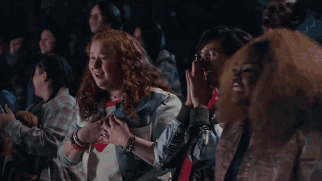 a girl with red hair is laughing with a group of people