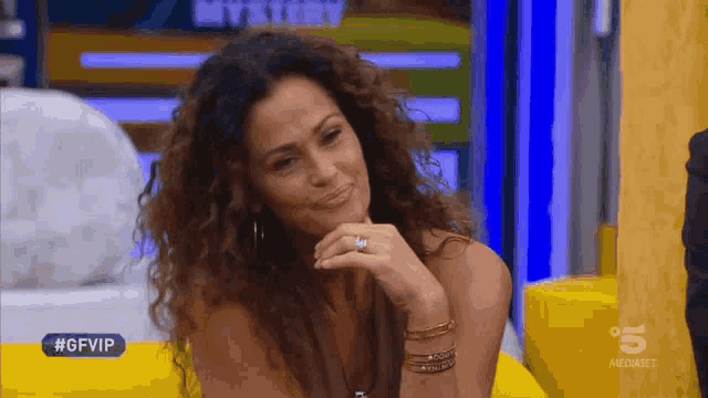 a woman with curly hair is sitting in front of a sign that says " mystery "