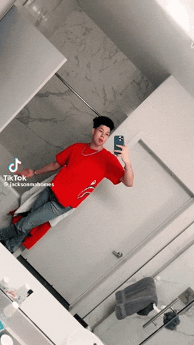 a man in a red shirt is taking a picture of himself