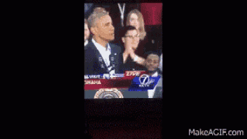 a man is giving a speech in front of a crowd and the number 7 is on the screen