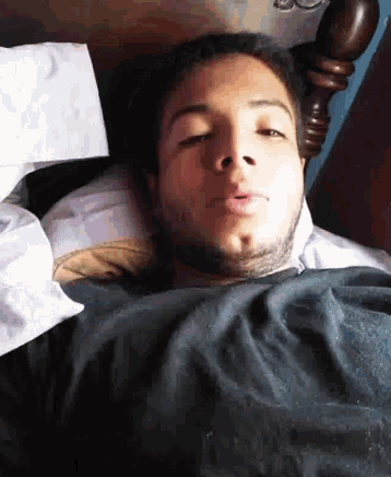 a young man is laying in bed with his eyes closed