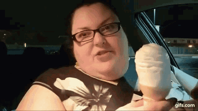 a woman is sitting in a car holding an ice cream cone