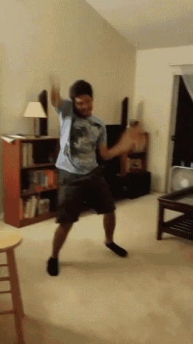 a man is dancing in a living room in front of a bookcase