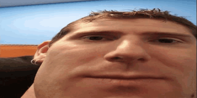a close up of a man 's face against a blue wall
