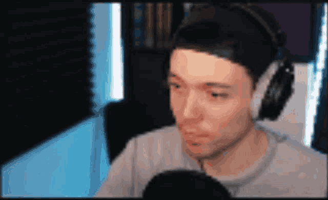 a man wearing headphones is sitting in front of a microphone and looking at the camera .