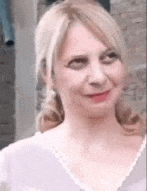 a close up of a woman making a funny face while wearing a purple shirt .