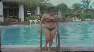 a woman in a bikini is getting out of a swimming pool with the letters v on the bottom right