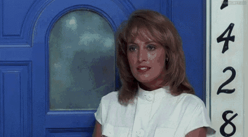 a woman in a white shirt is standing in front of a blue door with the number 428 on it .