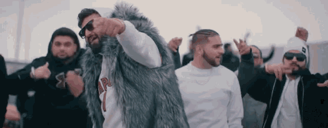 a group of men are dancing and one of them is wearing a fur coat with the number 1 on it .