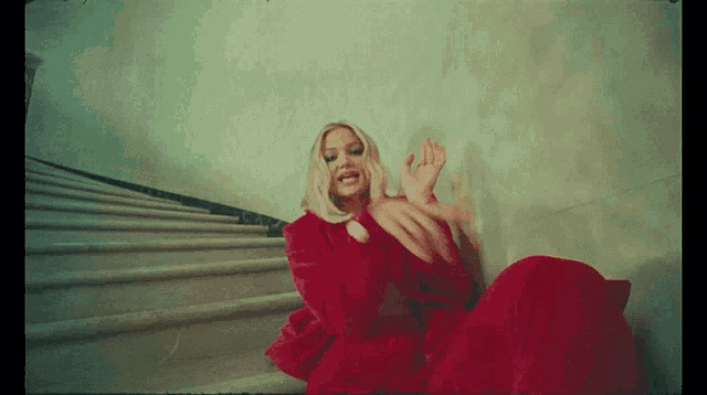 a woman in a red dress is sitting on some stairs