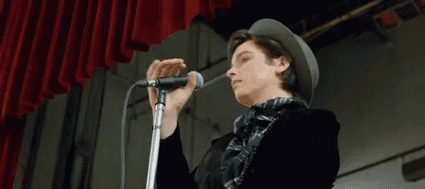 a man in a hat is singing into a microphone .