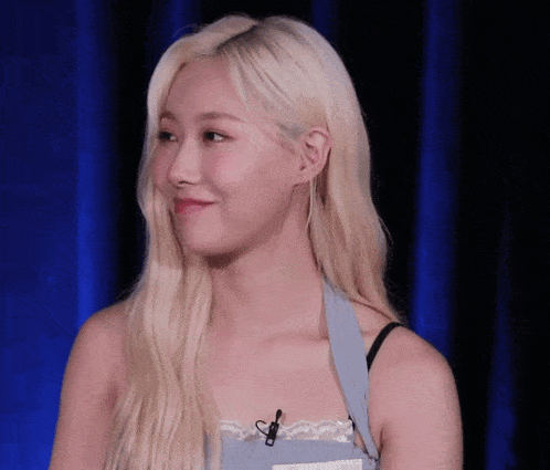 a woman with blonde hair wearing a blue apron and a black bra
