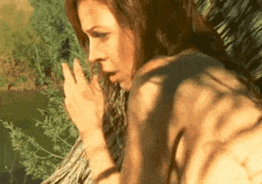 a woman is standing next to a tree and covering her mouth with her hand