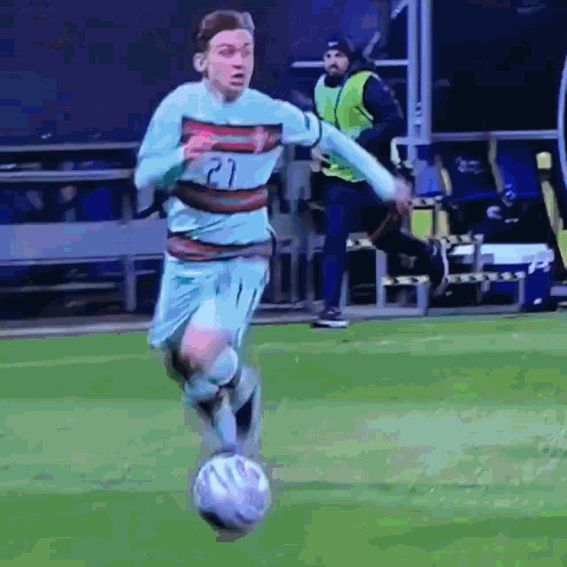 a soccer player with the number 21 on his jersey is running with the ball