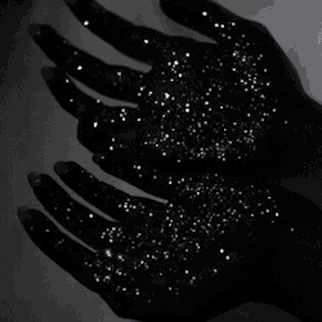 a person 's hands are filled with stars and sparkles in the dark