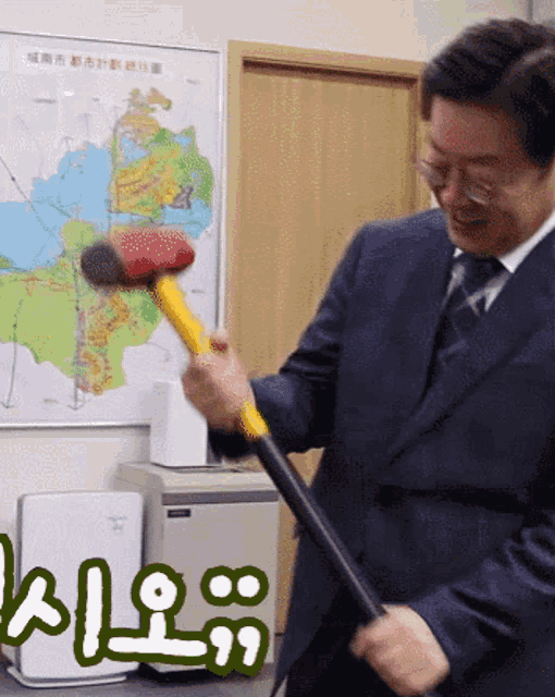 a man in a suit and tie is holding a hammer in front of a map with chinese writing on it