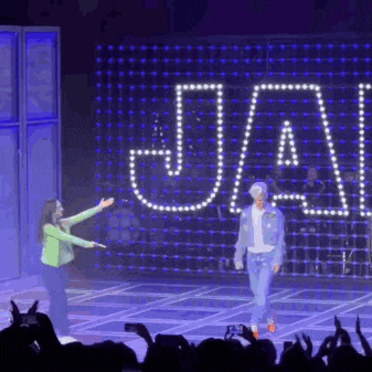 a man and a woman are standing on a stage in front of a sign that says ja .