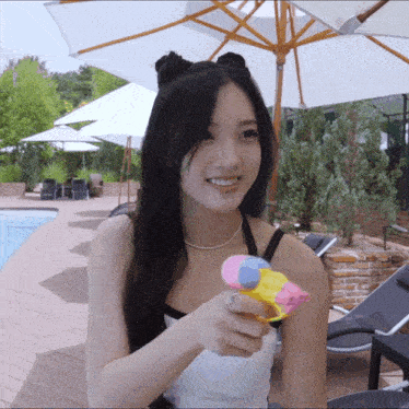 a girl is holding a water gun in front of a pool