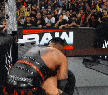 a wrestler is kneeling down in front of a sign that says raw