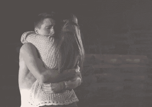 a black and white photo of a man and woman hugging each other .