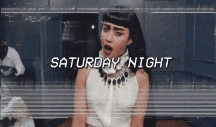 a woman in a white dress is standing in front of a sign that says saturday night