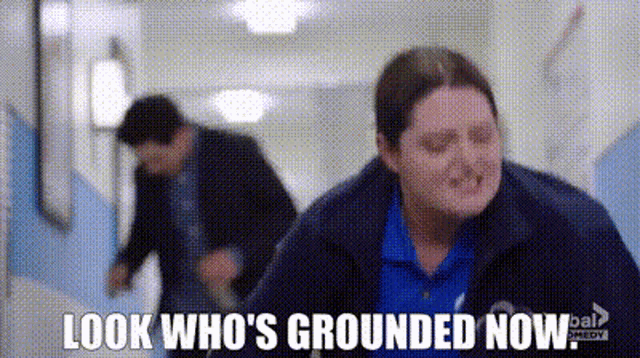 a man and a woman are walking down a hallway and the woman is saying `` look who 's grounded now `` .