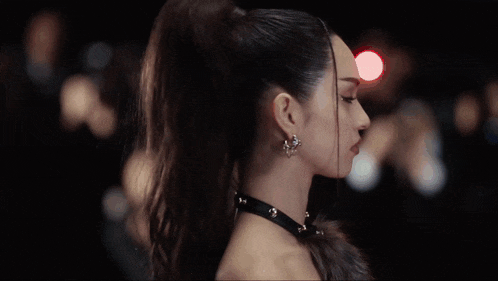 a woman with a ponytail is wearing a choker and earrings