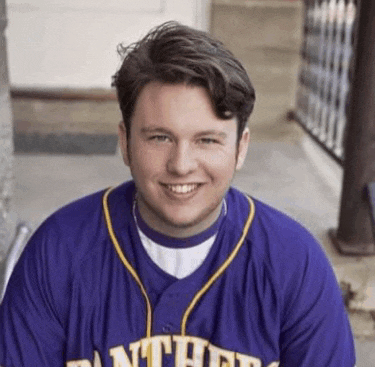 a young man wearing a purple panthers jersey is smiling for the camera .
