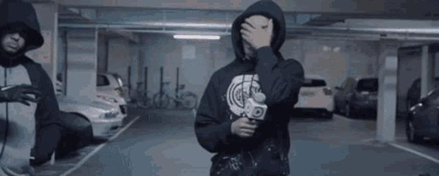 a man in a hoodie holds a camera in a parking lot