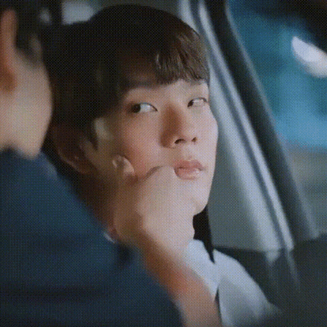 a man is putting his hand on a young boy 's face while sitting in a car .