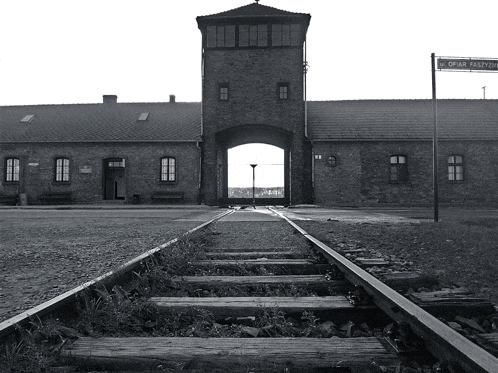 a black and white photo of a train track leading to a building with a sign that says ' l. o. '