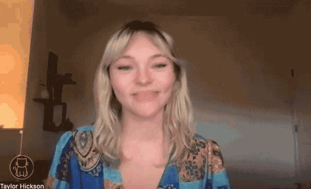 a woman is smiling in front of a screen with the name taylor hickson on it
