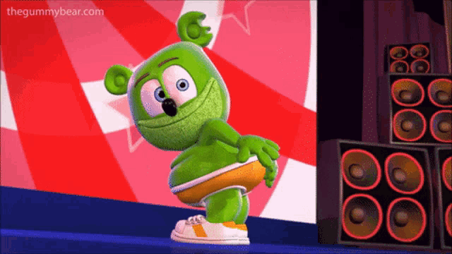 a gummy bear is dancing in front of speakers with the website thegummybear.com in the background