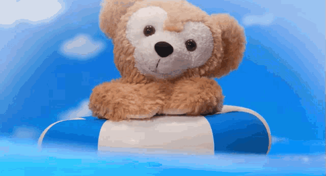 a teddy bear is sitting on a blue and white striped float