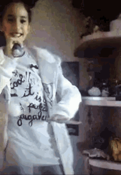 a girl wearing a t-shirt that says " cool " is standing in front of a shelf of food